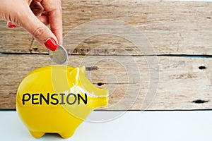 Putting money in a yellow piggy bank for pension, social security concept