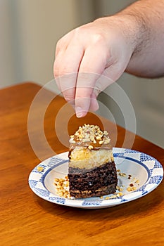 Putting nut topping on a cake slice covered in caramel