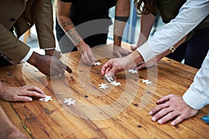 Putting the pieces in place. a group of unidentifiable businesspeople building a puzzle together.