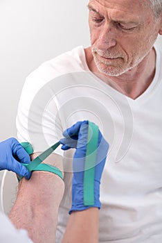 Putting a tourniquet on the arm of a patient photo