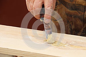 Putty knife in old man`s hand. Removing paint from a wood surface. Preparation of boards before impregnation with