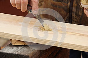 Putty knife in old man`s hand. Removing paint from a wood surface. Preparation of boards before impregnation with