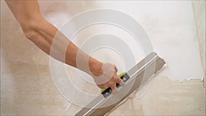 Construction worker with long trowel plastering a wall. Putty walls