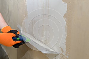 Puttying the wall with plaster putty using a wide spatula