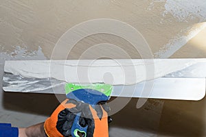 Puttying the wall with plaster putty using a wide spatula