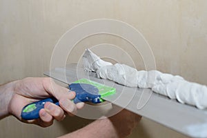 Puttying the wall with plaster putty using a wide spatula photo