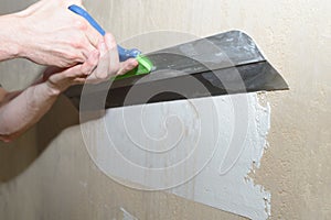 Puttying the wall with plaster putty using a wide spatula photo