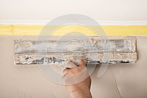 Puttying the walls with a spatula, repairing walls removing irregularities photo