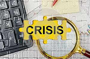 Puzzle with a calculator, magnifying glasses and financial documents in the center inscription -CRISIS