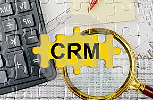 Puzzle with a calculator, magnifying glasses and financial documents in the center inscription -CRM