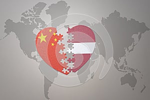 Puzzle heart with the national flag of china and latvia on a world map background. Concept