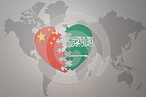 Puzzle heart with the national flag of china and saudi arabia on a world map background. Concept