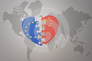 Puzzle heart with the national flag of european union and china on a world map background. Concept