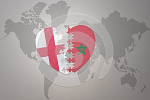 puzzle heart with the national flag of morocco and england on a world map background.Concept