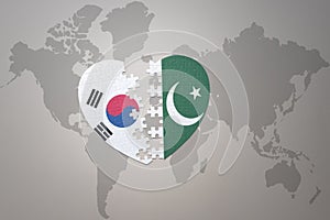Puzzle heart with the national flag of pakistan and south korea on a world map background. Concept