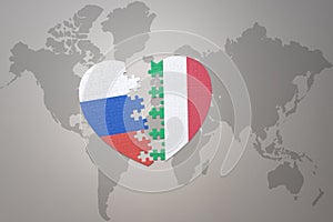 Puzzle heart with the national flag of russia and italy on a world map background. Concept