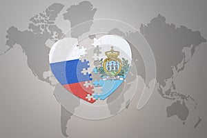 Puzzle heart with the national flag of russia and san marino on a world map background. Concept