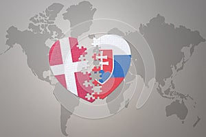 Puzzle heart with the national flag of slovakia and denmark on a world map background. Concept