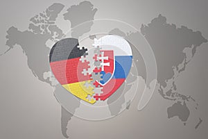 Puzzle heart with the national flag of slovakia and germany on a world map background. Concept