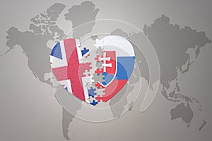 Puzzle srdce s národní vlajkou slovenska a Velké Británie na pozadí mapy světa. Koncept