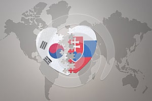 Puzzle srdce s národní vlajkou Slovenska a Jižní Koreje na pozadí mapy světa. Koncept