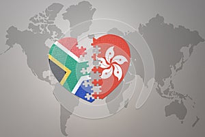 Puzzle heart with the national flag of south africa and hong kong on a world map background. 3D illustration