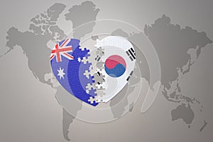 Puzzle heart with the national flag of south korea and australia on a world map background. Concept