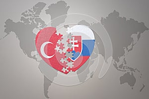 Puzzle srdce s národnou vlajkou Turecka a slovenska na pozadí mapy sveta. Koncept
