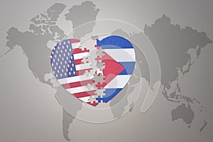 Puzzle heart with the national flag of united states of america and cuba on a world map background. Concept