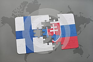 Puzzle s národnou vlajkou Fínska a Slovenska na pozadí mapy sveta.