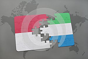 puzzle with the national flag of indonesia and sierra leone on a world map background.
