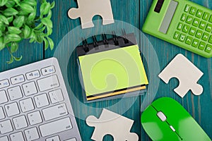 Puzzle pieces, calculator, sketchbook, computer keyboard and mouse on blue wooden background