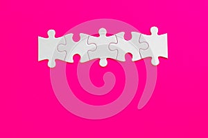 Puzzle pieces on fuchsia background.
