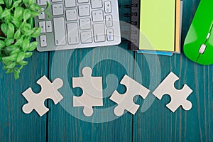 Puzzle pieces, sketchbook, computer keyboard and mouse on blue wooden background