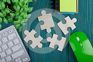 Puzzle pieces, sketchbook, computer keyboard and mouse on blue wooden background