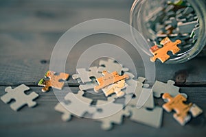 puzzle pieces spilling from glass jar on wooden background