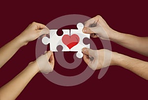 Puzzle with a red heart in the hands of a loving couple. Valentine`s day concept.On a isolated background