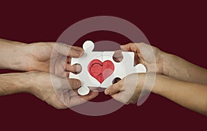 Puzzle with a red heart in the hands of a loving couple. Valentine`s day concept.On a isolated background