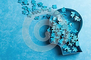 Puzzle in a shape of human head losing pieces as brain damage or loss memory on blue background