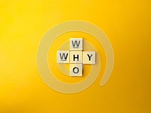 Puzzle of wooden alphabet blocks, with "why" and "who" words on yellow background