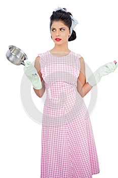 Puzzled black hair model holding a pan and wearing rubber gloves