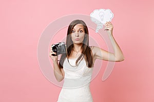 Puzzled bride woman in wedding dress hold retro vintage photo camera, Say cloud speech bubble with lightbulb choosing