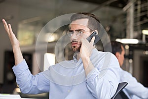 Puzzled businessman talking on phone in office photo