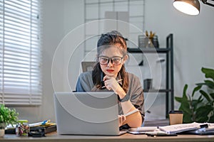 Puzzled confused asian woman thinking hard concerned about online problem solution looking at laptop screen, worried