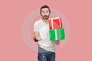 Puzzled confused man holding two present boxes in hands, looking at camera with surprised expression