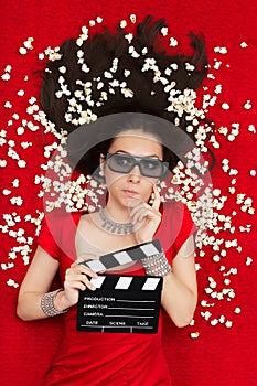 Puzzled Girl with 3D Cinema Glasses, Popcorn and Director Clapboard