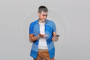 Puzzled man looking at the screan of a smartphone being shocked.