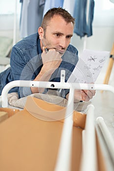 puzzled man reading instructions to assemble furniture