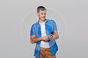 Puzzled man with a smartphone is shocked and sceptic.