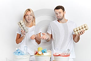 Puzzled man and woman hesitating how to reuse carton of eggs